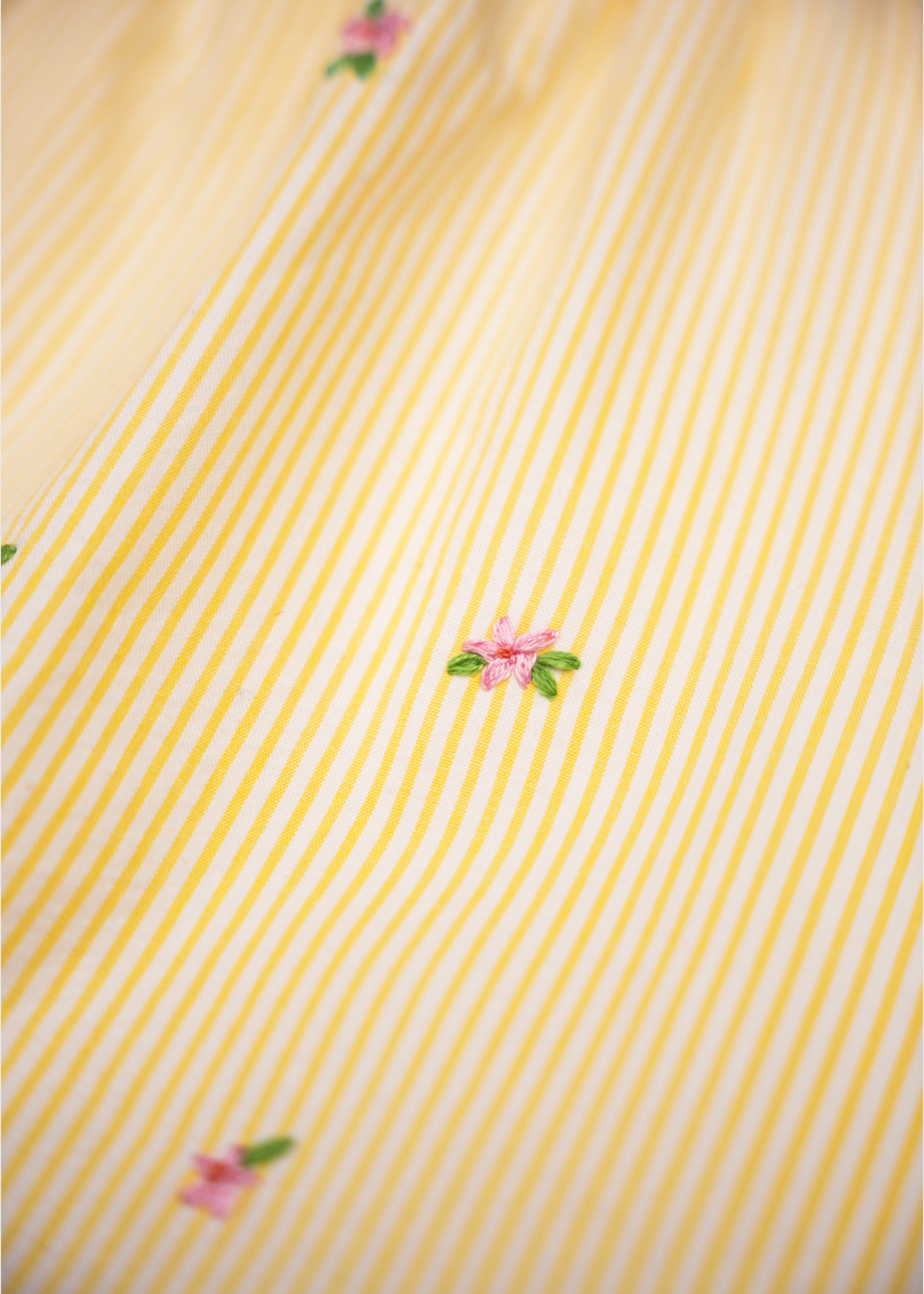 Detalhe de flores bordadas à mão em algodão anarruga listrado amarelo