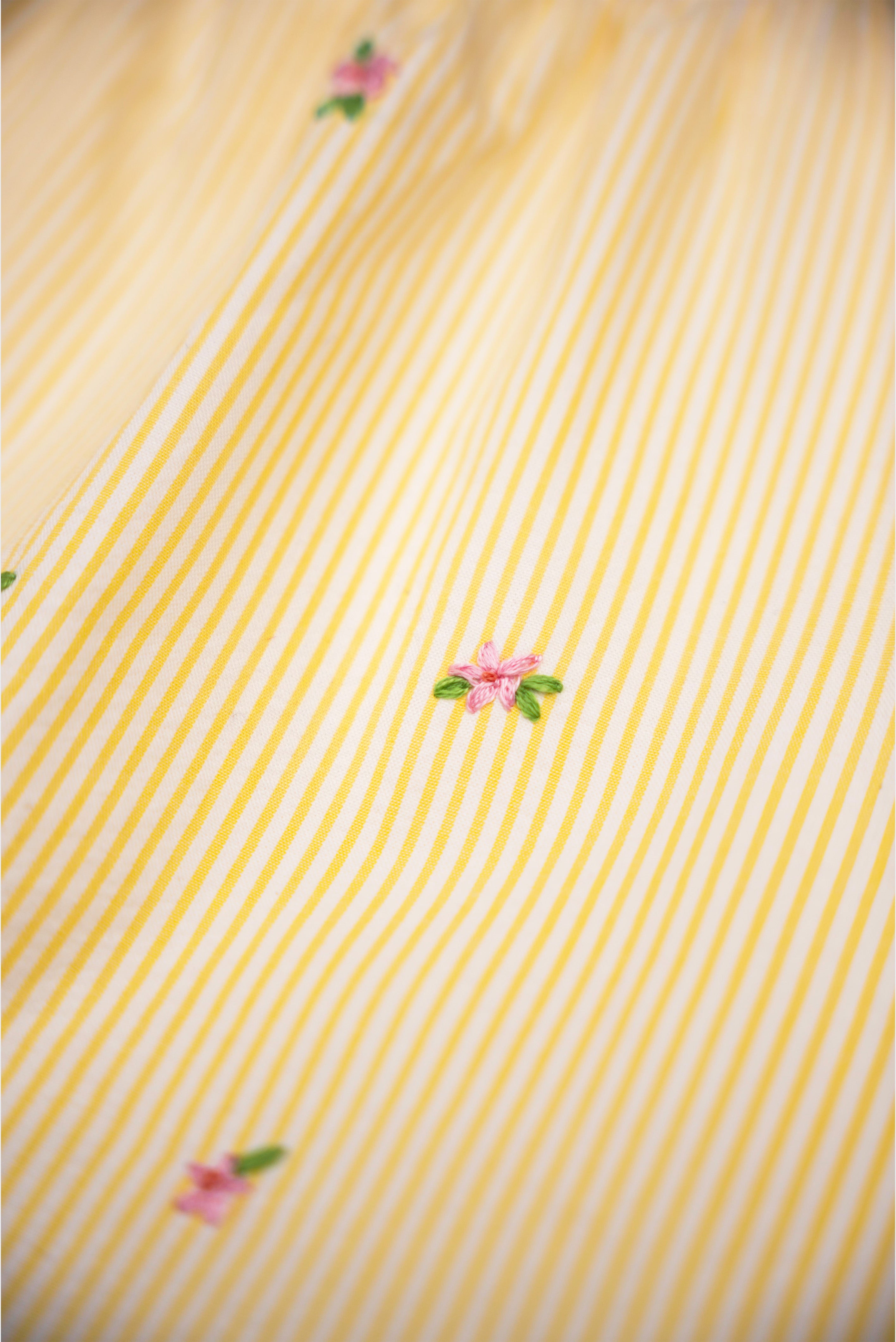 Detalhe de flores bordadas à mão em algodão anarruga listrado amarelo