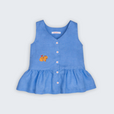 Bata Lola infantil em linho puro azul com capivara bordada à mão e barra franzida, vista de frente