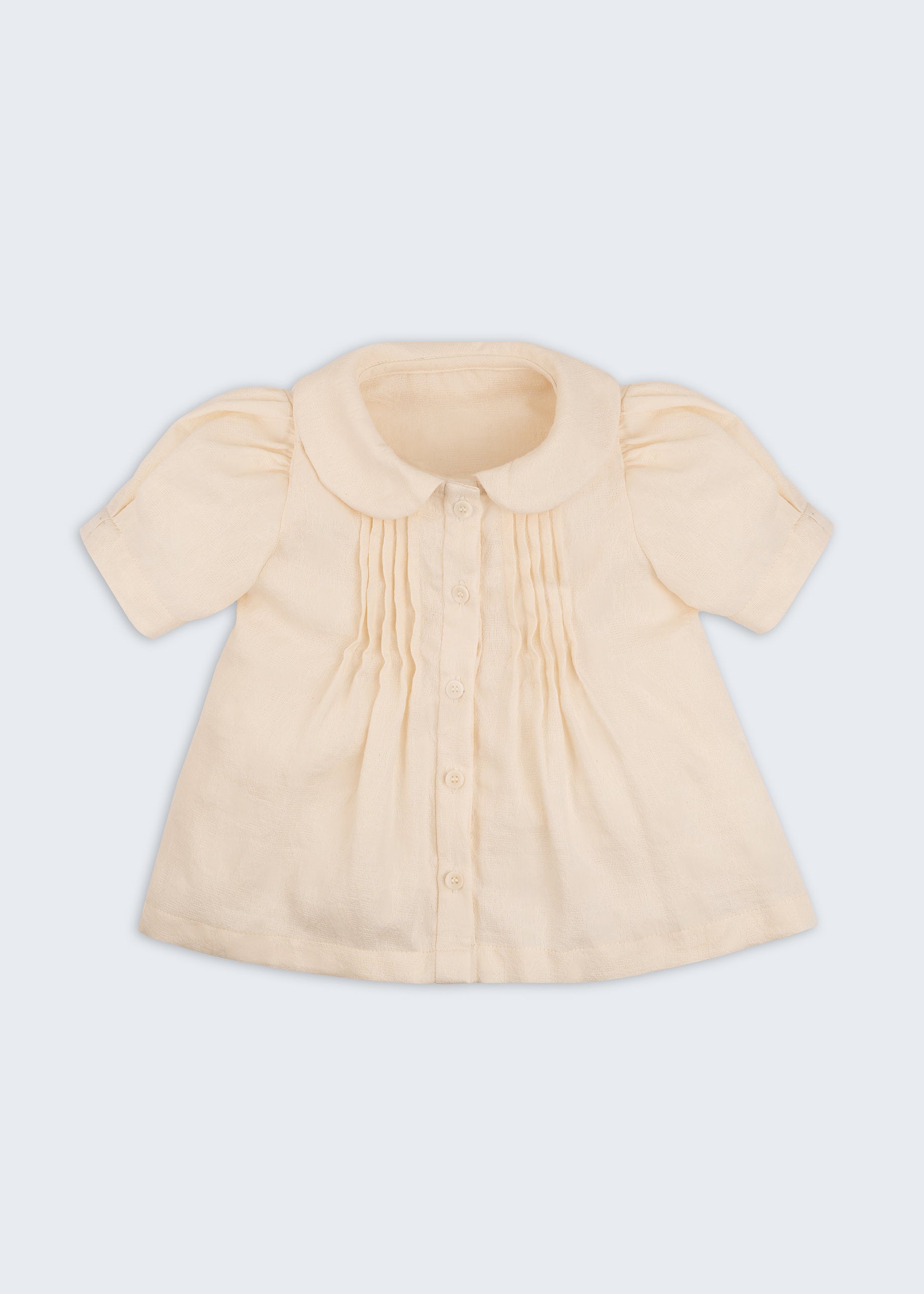 Bata infantil de menina off-while com mangas curtas levemente bufantes, gola Peter Pan arredondada e pregas no peitilho, vista de frente.