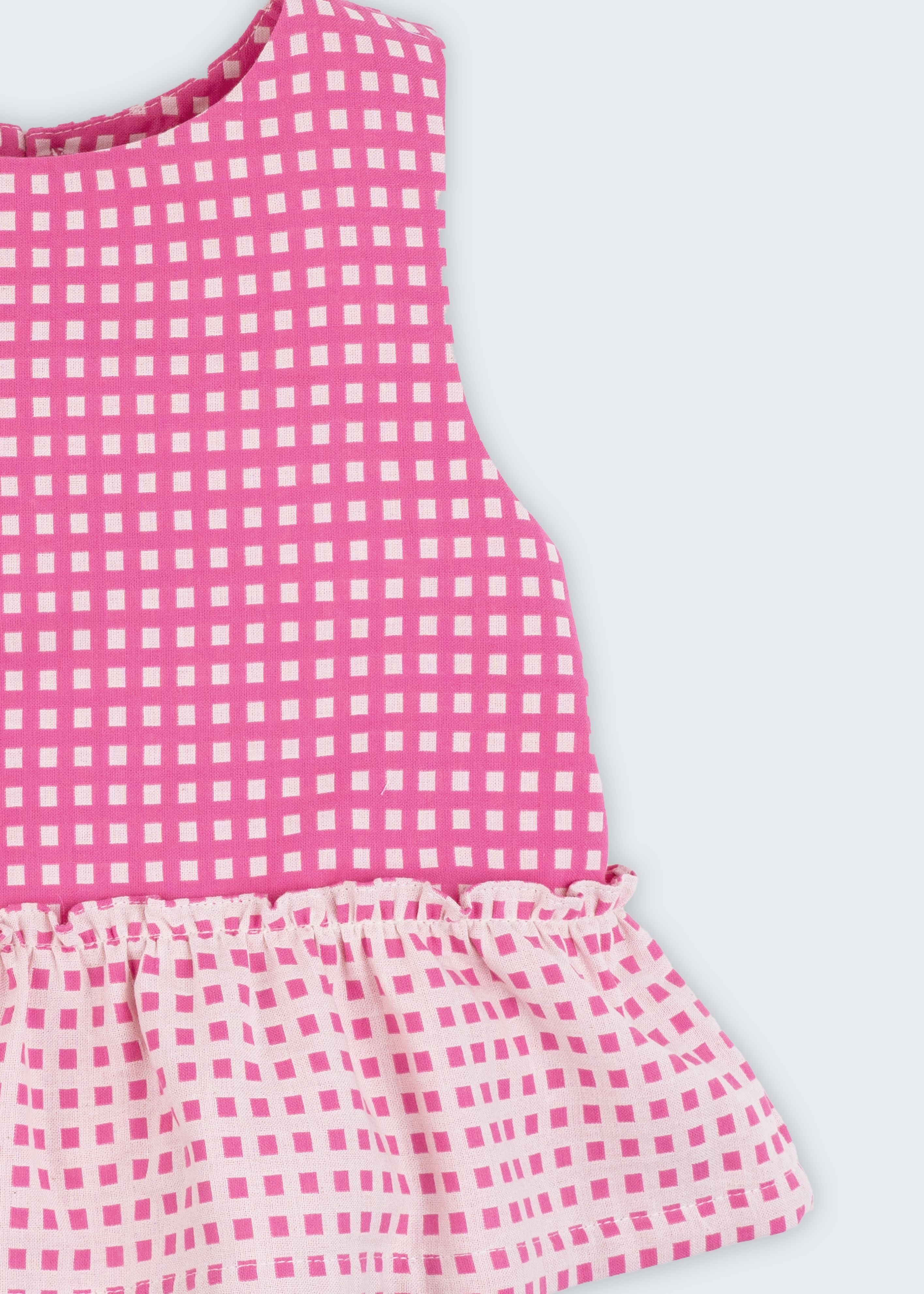 Bata infantil para menina em algodão BCI com estampa xadrez vichy rosa e babado, vista de frente em detalhe.