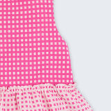Bata infantil para menina em algodão BCI com estampa xadrez vichy rosa e babado, vista de frente em detalhe.