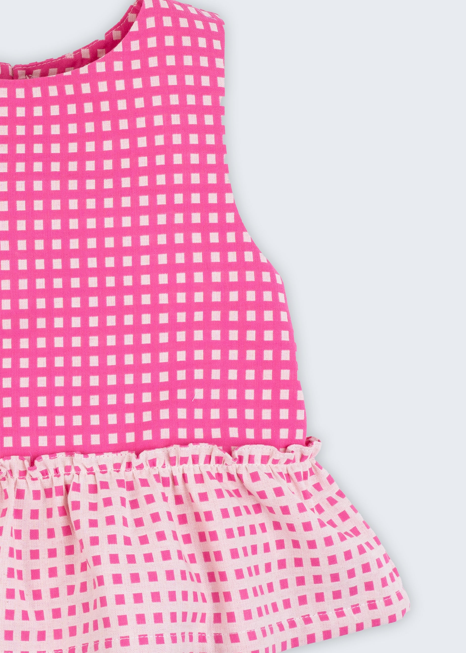 Bata infantil para menina em algodão BCI com estampa xadrez vichy rosa e babado, vista de frente em detalhe.