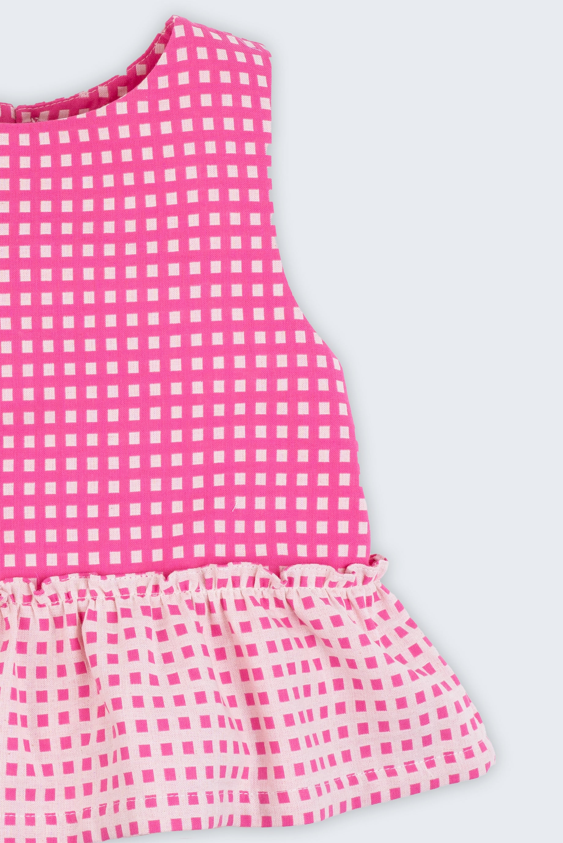 Bata infantil para menina em algodão BCI com estampa xadrez vichy rosa e babado, vista de frente em detalhe.