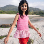 Menina usando bata com estampa xadrez vichy rosa e barra drapeada com babado em padrão invertido.