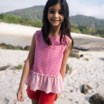 Menina usando bata com estampa xadrez vichy rosa e barra drapeada com babado.
