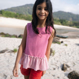 Menina usando bata com estampa xadrez vichy rosa e barra drapeada com babado.