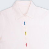 Detalhe da gola e bordados de peixes coloridos em camisa feminina de linho branco Oli e Sofi