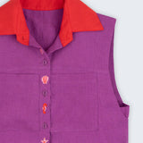 Camisa feminina sem mangas em linho roxo com gola vermelha e abotoamento bordado com conchas e cavalos-marinhos, vista em detalhe.