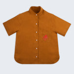 Camisa feminina adulto em linho puro terracota com gola padre, bolso bordado à mão com polvo vermelho e botões brancos, vista de frente.