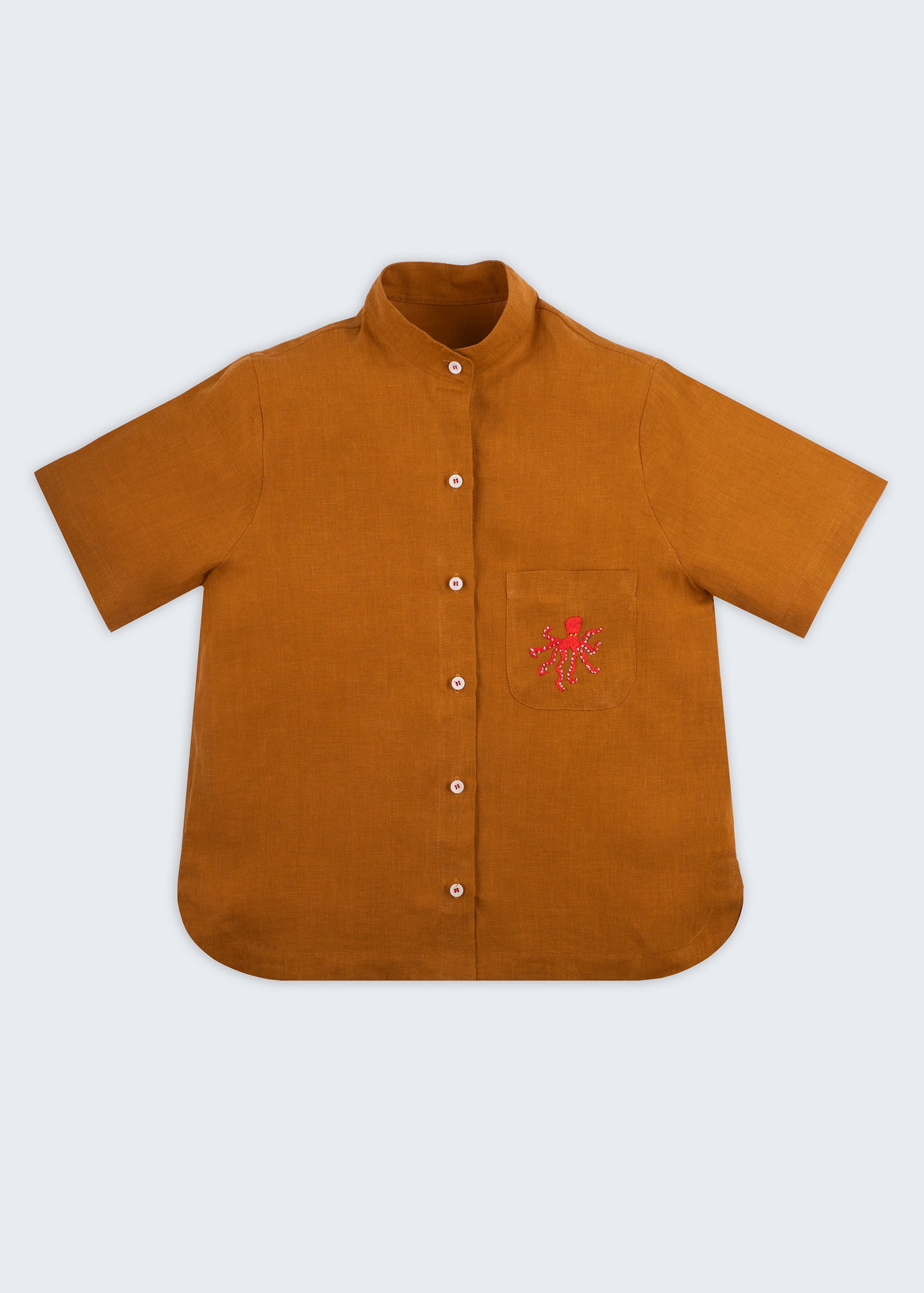 Camisa feminina adulto em linho puro terracota com gola padre, bolso bordado à mão com polvo vermelho e botões brancos, vista de frente.