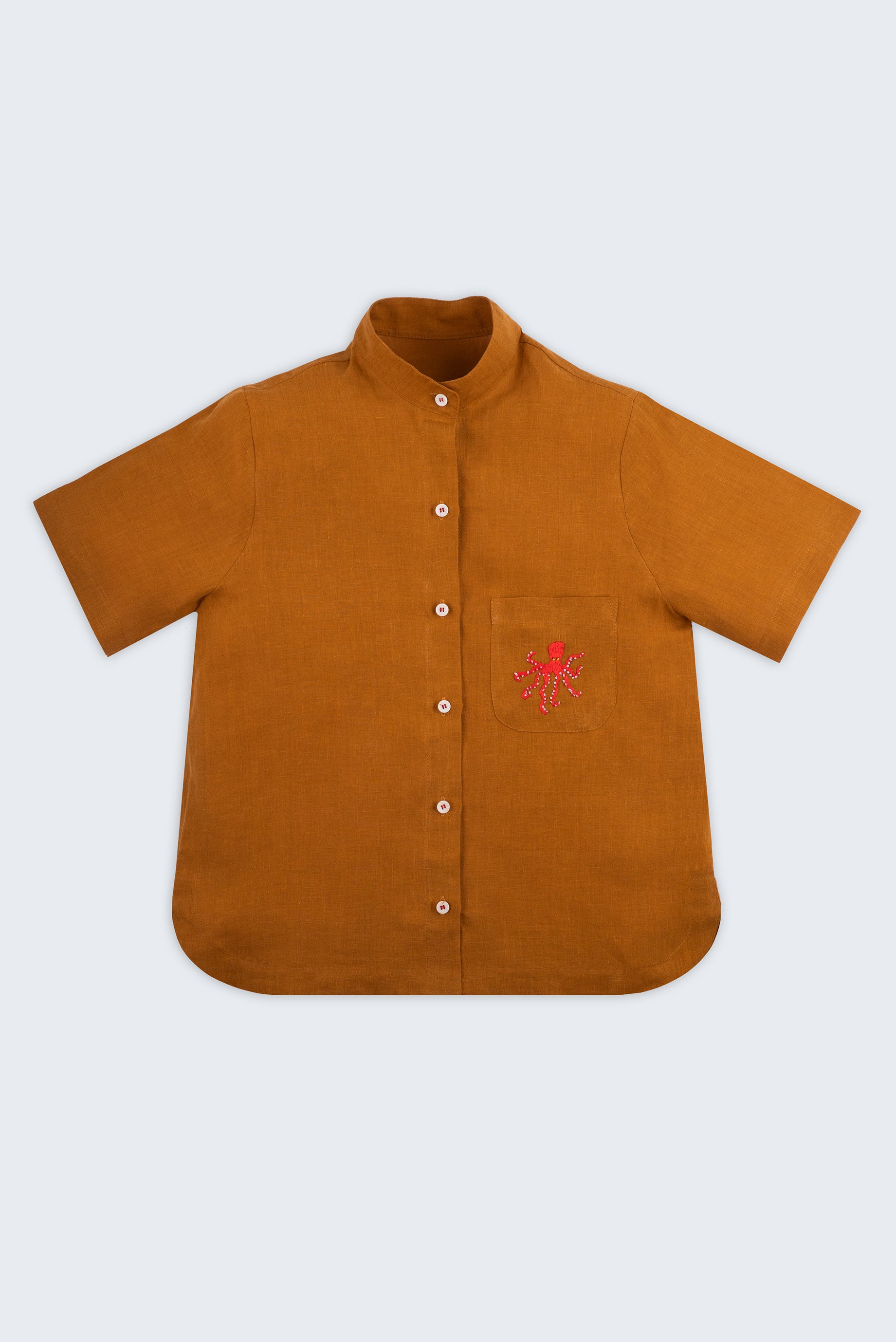 Camisa feminina adulto em linho puro terracota com gola padre, bolso bordado à mão com polvo vermelho e botões brancos, vista de frente.