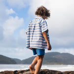 Menino de costas com camisa infantil listrada azul em algodão.