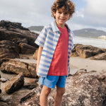 Menino com camisa infantil listrada azul em com peixes bordados, em sobreposição de camiseta.