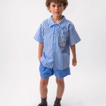 Menino usando Camisa Gil infantil em algodão listrado azul e branco com bolso e sol bordado à mão.