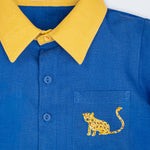 Detalhe da Camisa Tom infantil em linho azul com gola amarela, botões azuis e onça bordada à mão no bolso