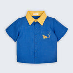 Camisa infantil Tom em linho puro azul com gola amarela e bordado à mão de onça no bolso frontal, vista de frente.