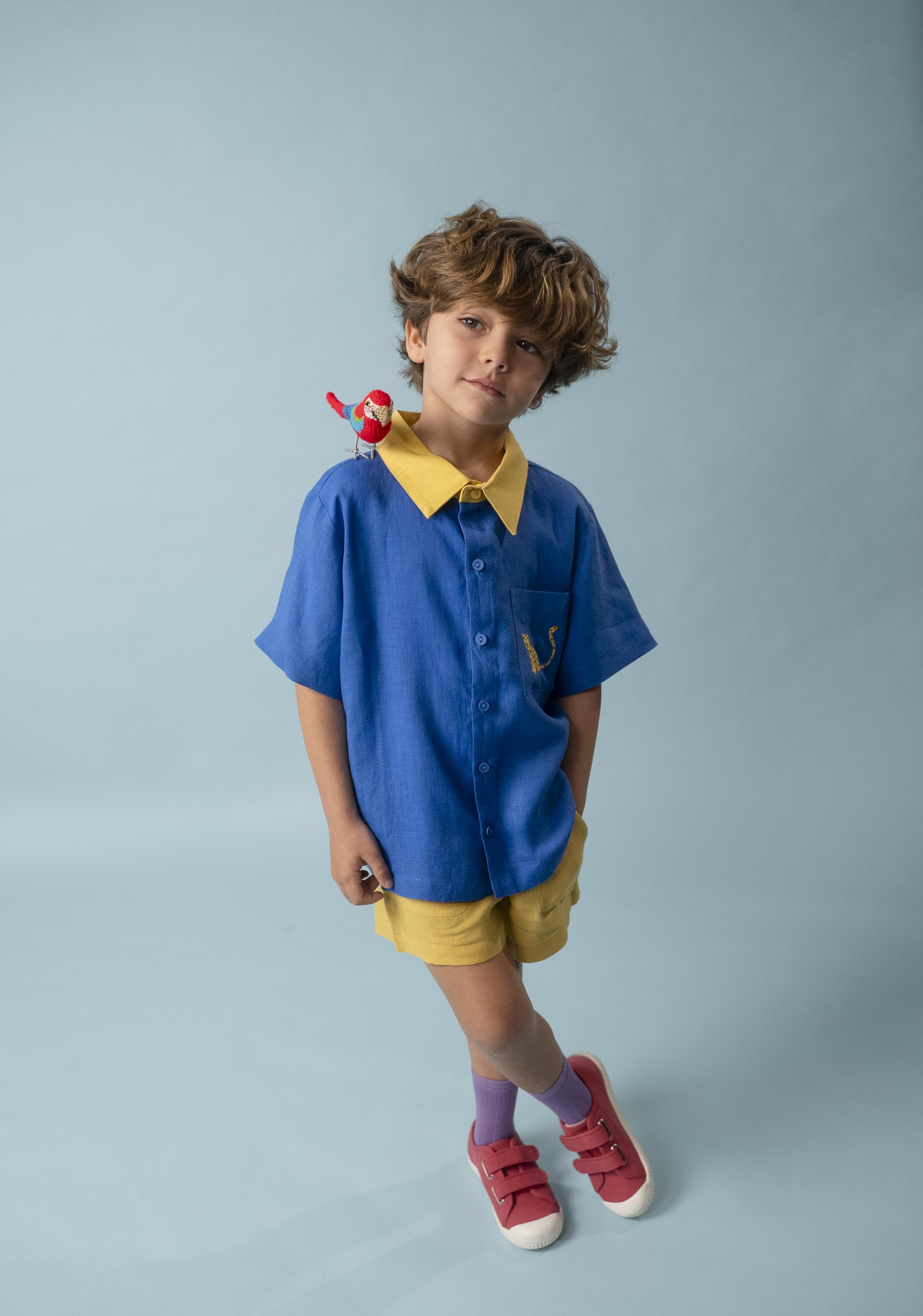 Menino usando Camisa Tom em linho azul e amarelo com bordado de onça, em look infantil colorido da coleção Nosso Brasil