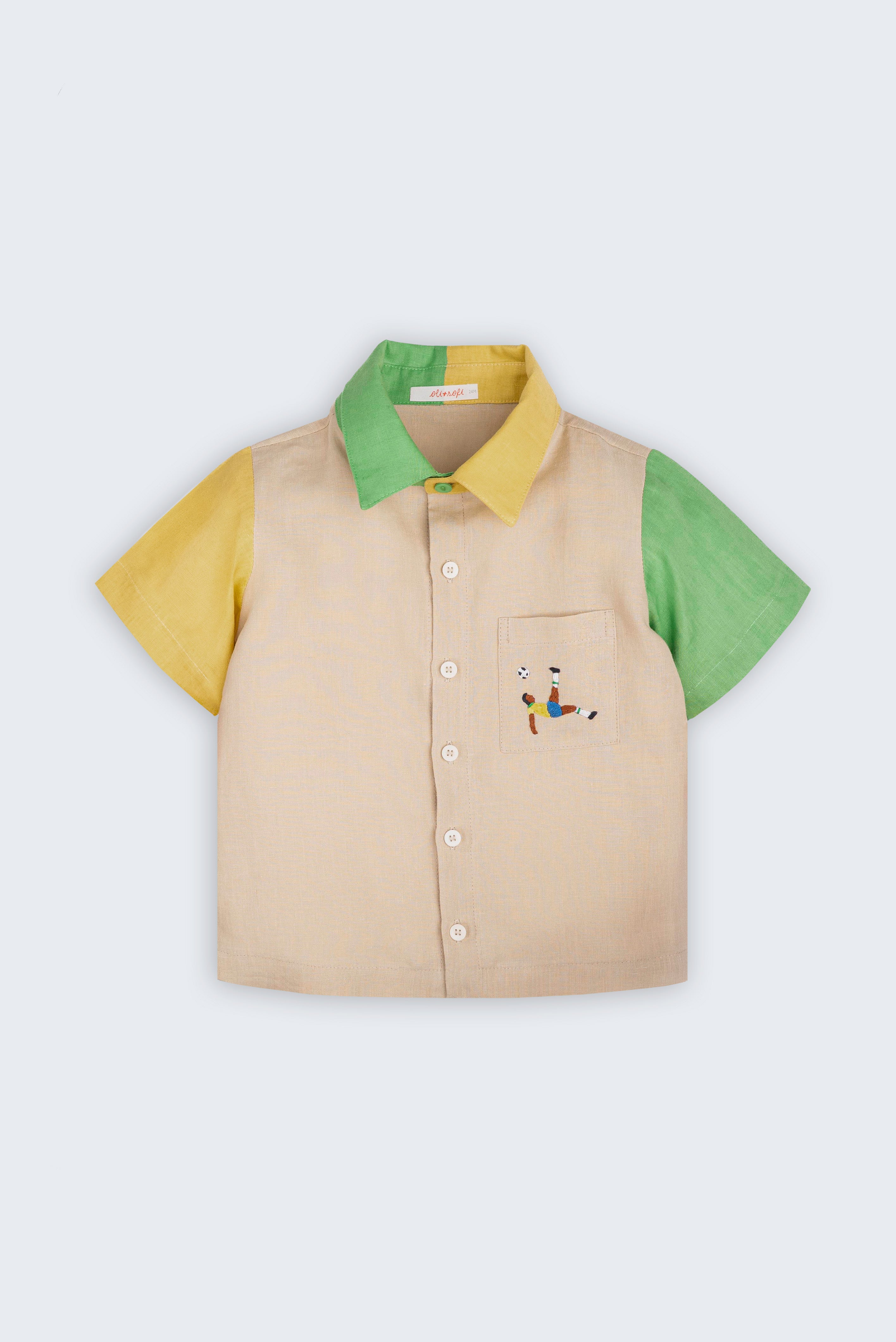 Camisa infantil em linho puro bege com mangas verde e amarela, gola bicolor e bordado de jogador de futebol no bolso, vista de frente