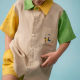 Menino usando camisa infantil em linho bege com mangas verde e amarela e bordado à mão de jogador no bolso