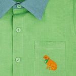 Camisa infantil em linho puro verde com gola verde aspargo e bordado à mão de cachorro caramelo no bolso, vista em detalhe