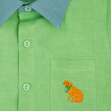 Camisa infantil em linho puro verde com gola verde aspargo e bordado à mão de cachorro caramelo no bolso, vista em detalhe