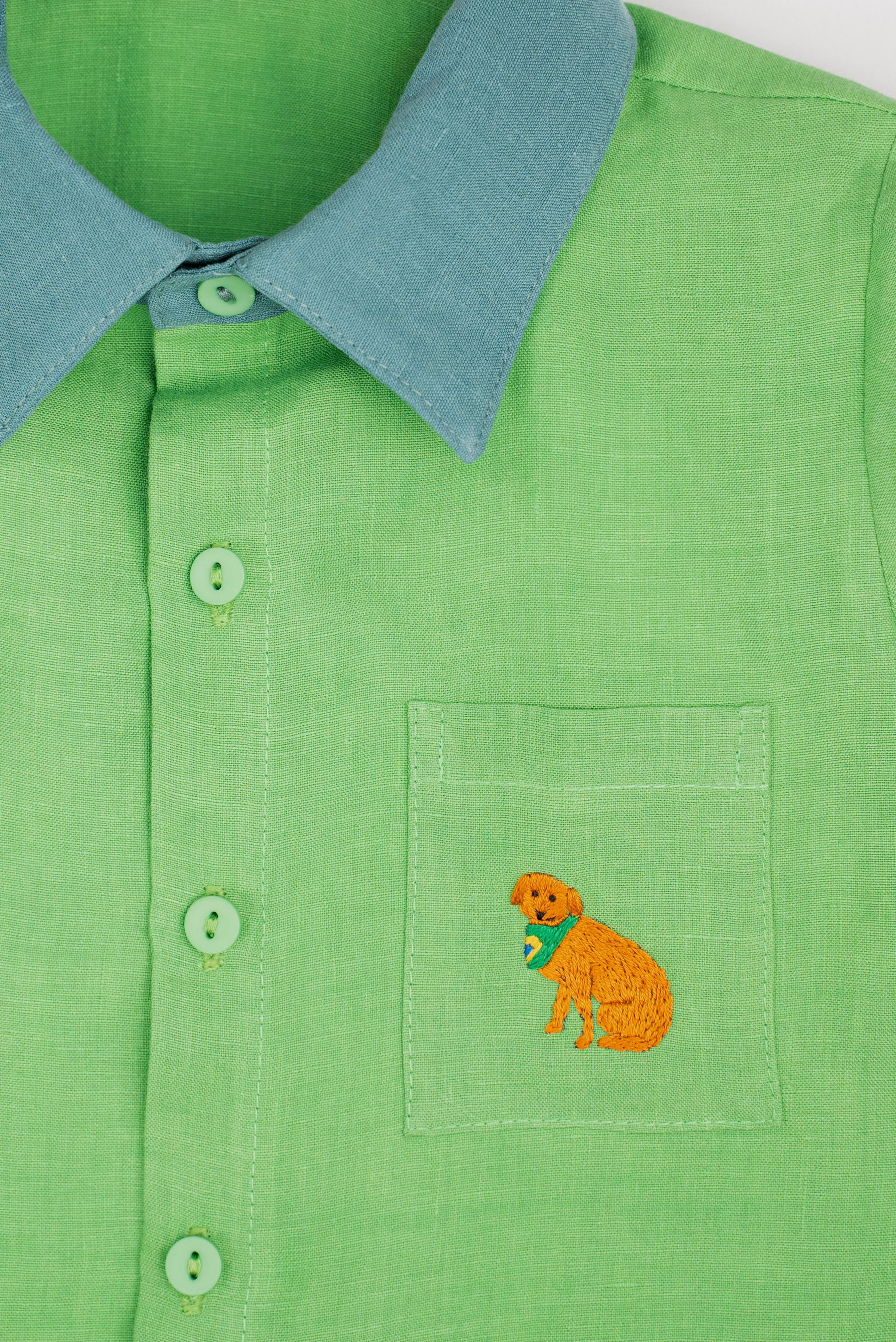 Camisa infantil em linho puro verde com gola verde aspargo e bordado à mão de cachorro caramelo no bolso, vista em detalhe