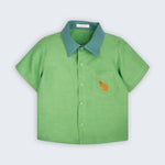 Camisa infantil Tom em linho verde com gola verde aspargo e cachorro caramelo bordado à mão no bolso frontal, vista de frente