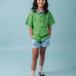 Menina usando Camisa Tom em linho verde com gola verde aspargo e bordado de cachorro caramelo no bolso