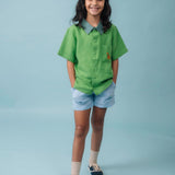 Menina usando Camisa Tom em linho verde com gola verde aspargo e bordado de cachorro caramelo no bolso