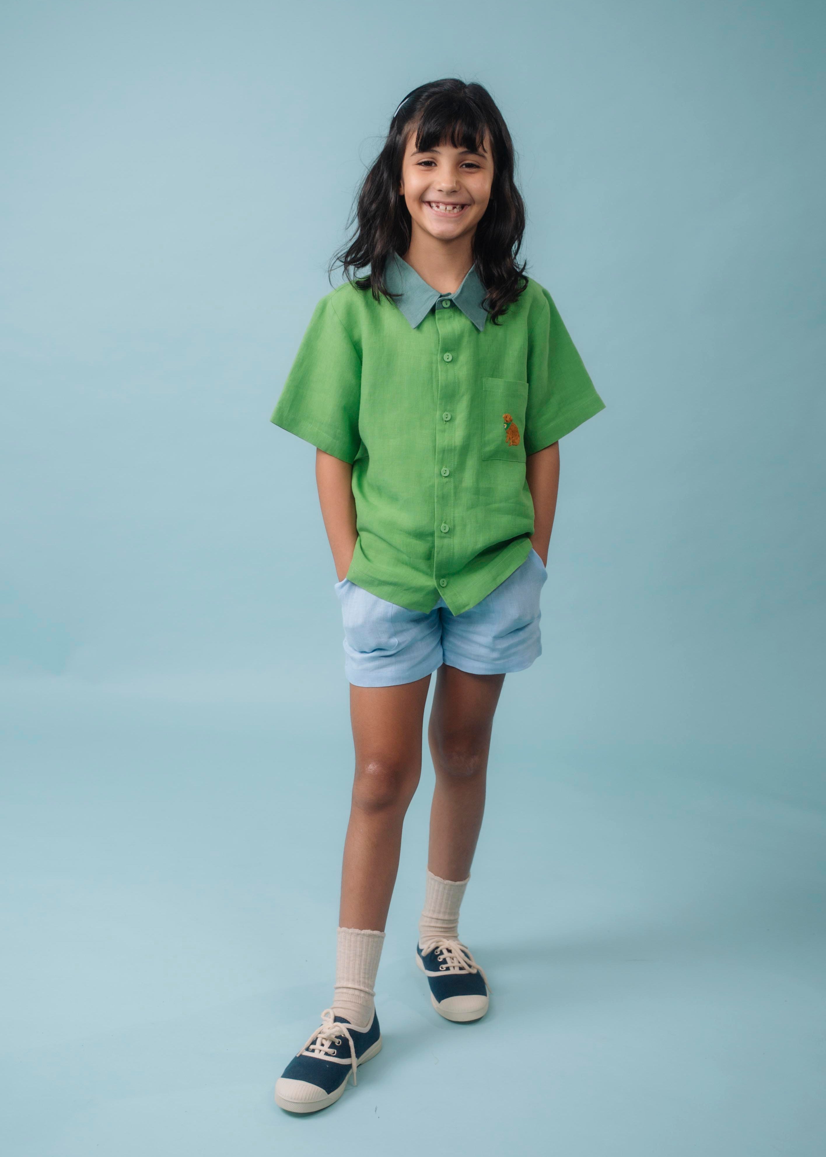 Menina usando Camisa Tom em linho verde com gola verde aspargo e bordado de cachorro caramelo no bolso