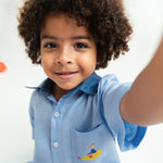 Close de menino usando camisa infantil em linho puro azul claro com bordado Yellow Submarine