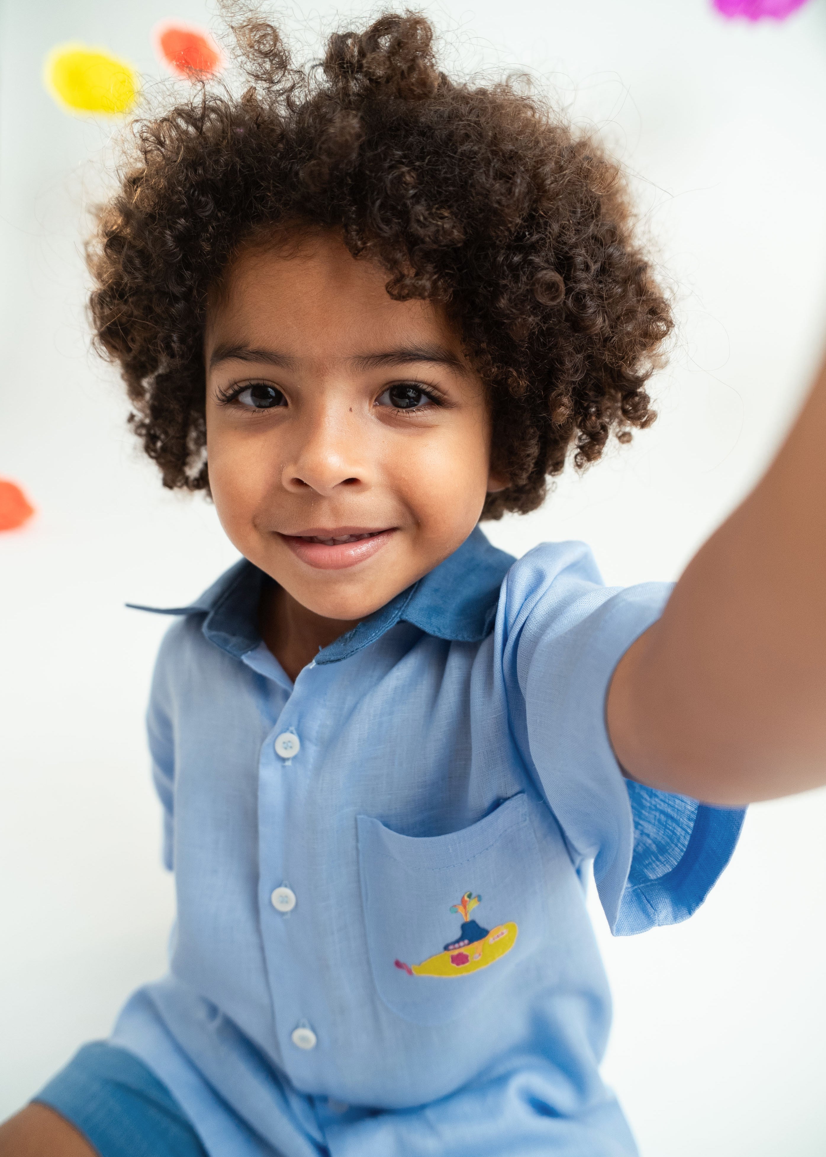 Close de menino usando camisa infantil em linho puro azul claro com bordado Yellow Submarine