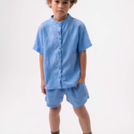 Menino usando Camisa Bento infantil em linho azul com peixinhos bordados à mão e shorts azul.