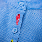 Close dos peixinhos bordados à mão entre os botões da Camisa Bento em linho azul fio tinto, com trama texturizada.