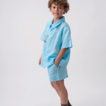 Menino usando Camisa Tom em linho azul turquesa com bordado de macaco e shorts coordenado.