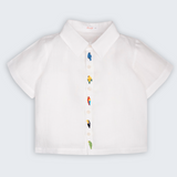 Camisa Tom infantil em 100% linho branco, vista frontal, com aves brasileiras bordadas à mão ao longo do fechamento.