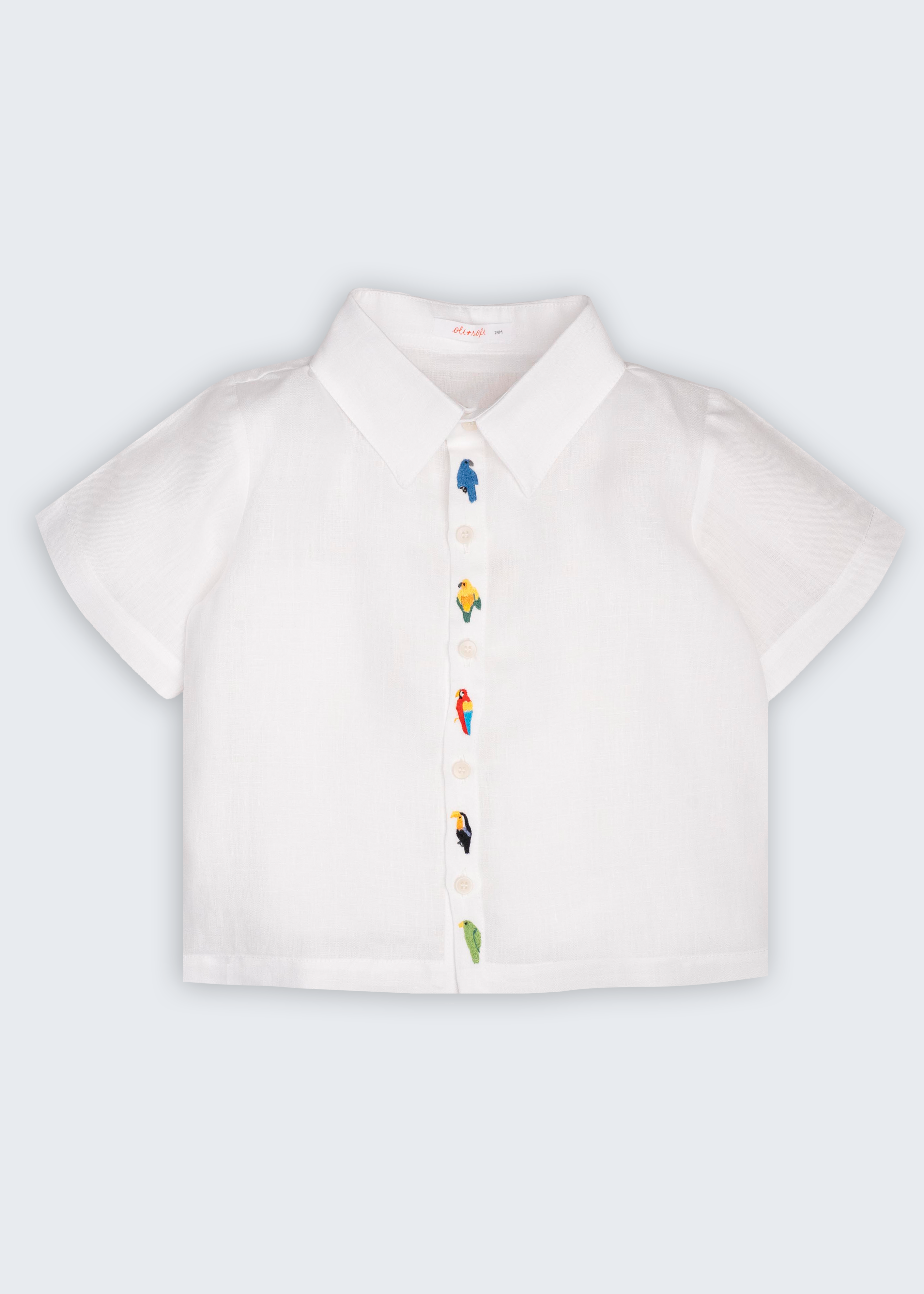 Camisa Tom infantil em 100% linho branco, vista frontal, com aves brasileiras bordadas à mão ao longo do fechamento.