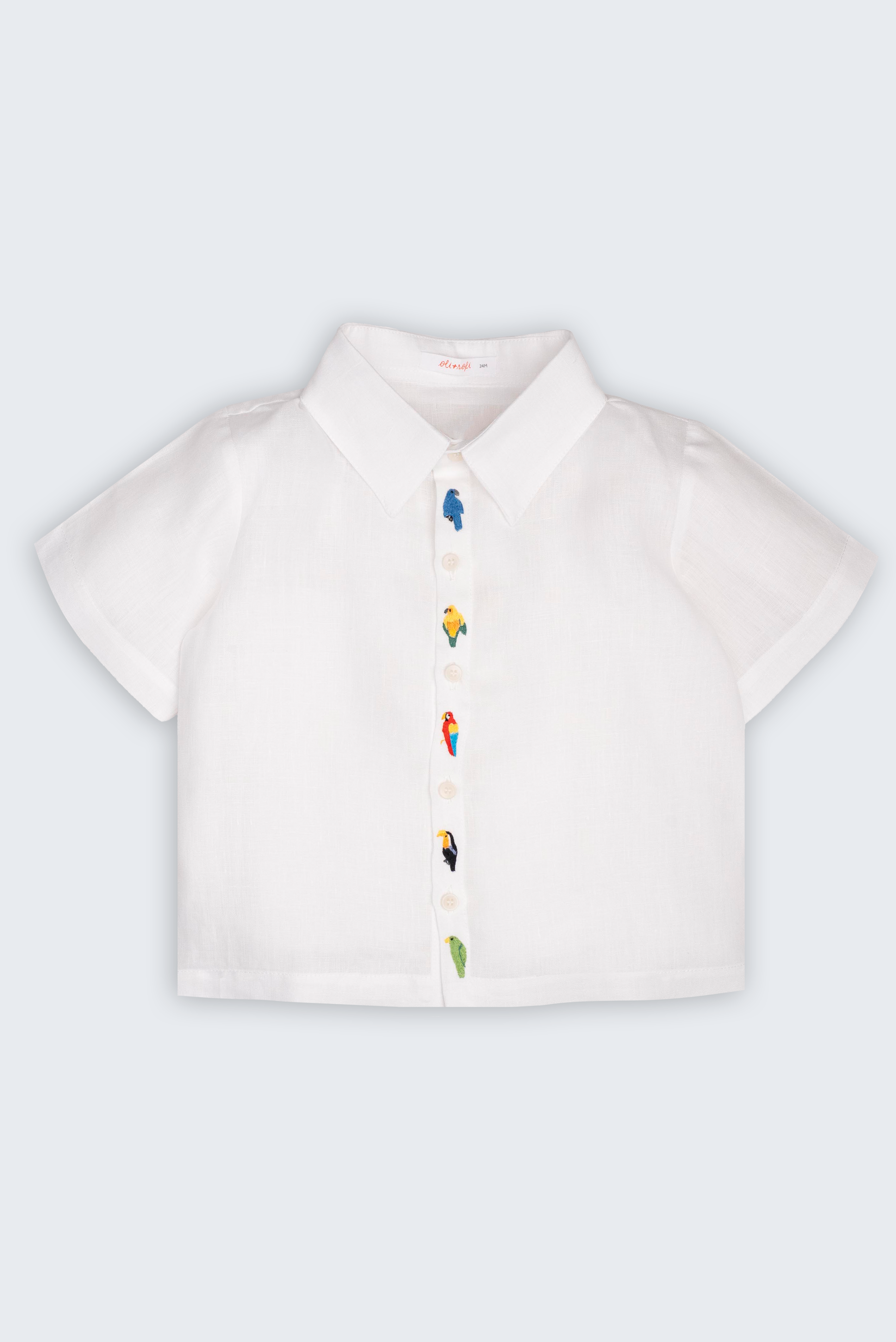 Camisa Tom infantil em 100% linho branco, vista frontal, com aves brasileiras bordadas à mão ao longo do fechamento.