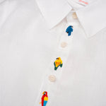 Detalhe da Camisa Tom infantil em linho branco com aves brasileiras bordadas à mão entre os botões.