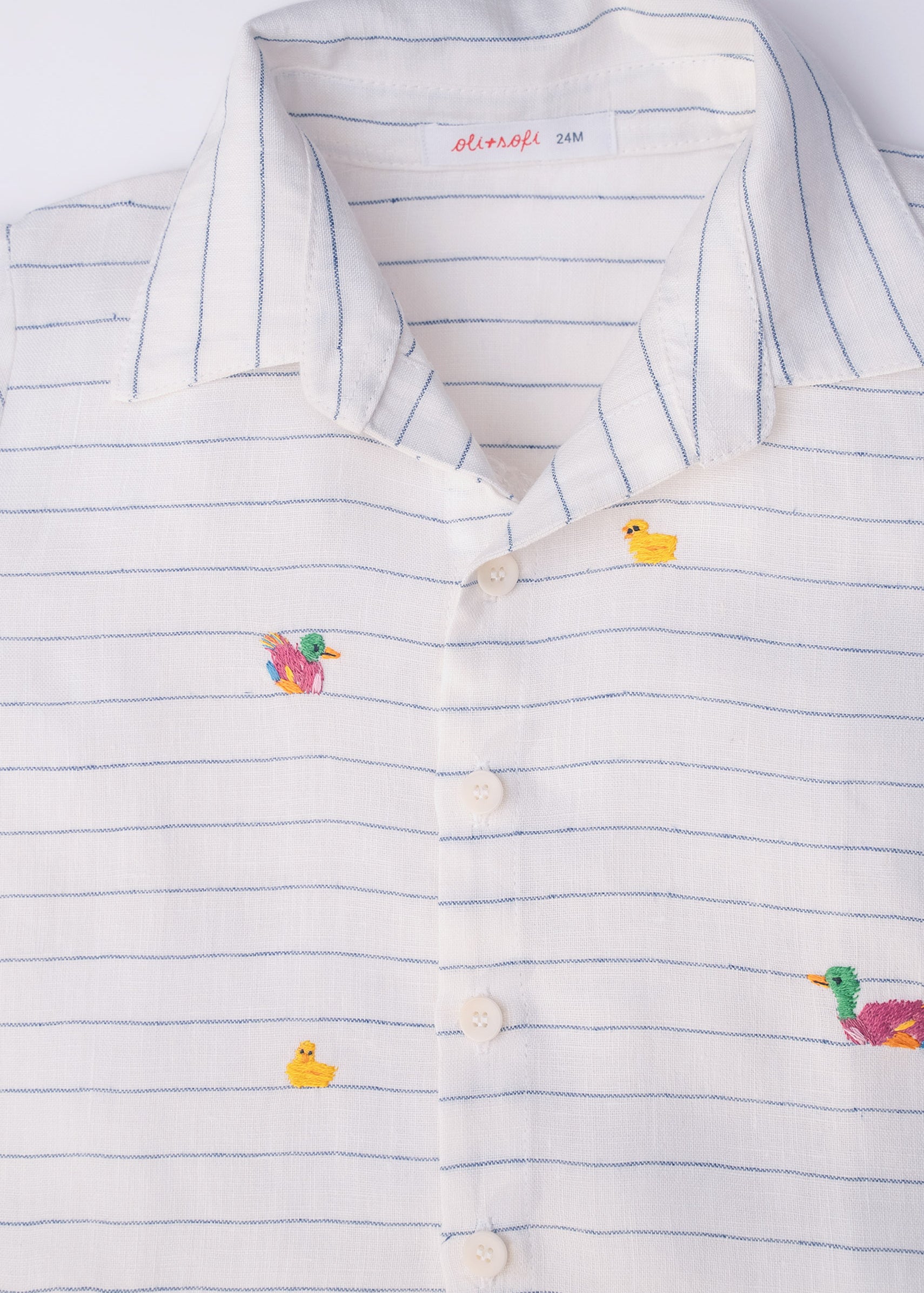 Camisa infantil listrada com patinhos bordados à mão com botões brancos, vista de frente em detalhe