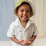 Menino usando camisa infantil listrada com patinhos bordados à mão e chapéu verde