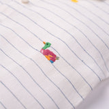 Detalhe do bordado artesanal de patinho colorido em camisa infantil listrada de linho claro