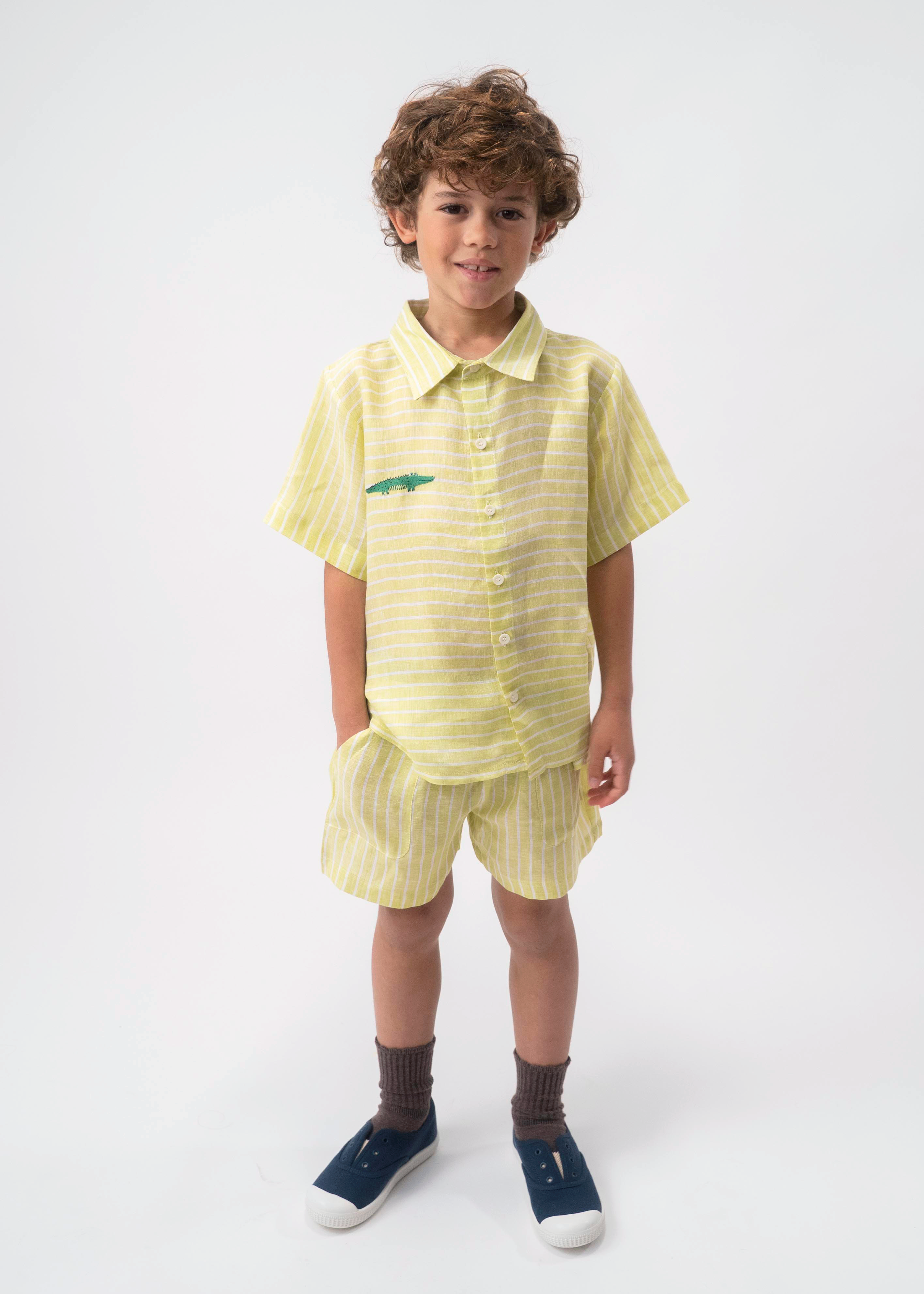 Menino usando Camisa Tom infantil em linho verde listrado com jacaré bordado, combinada com shorts no mesmo tecido.