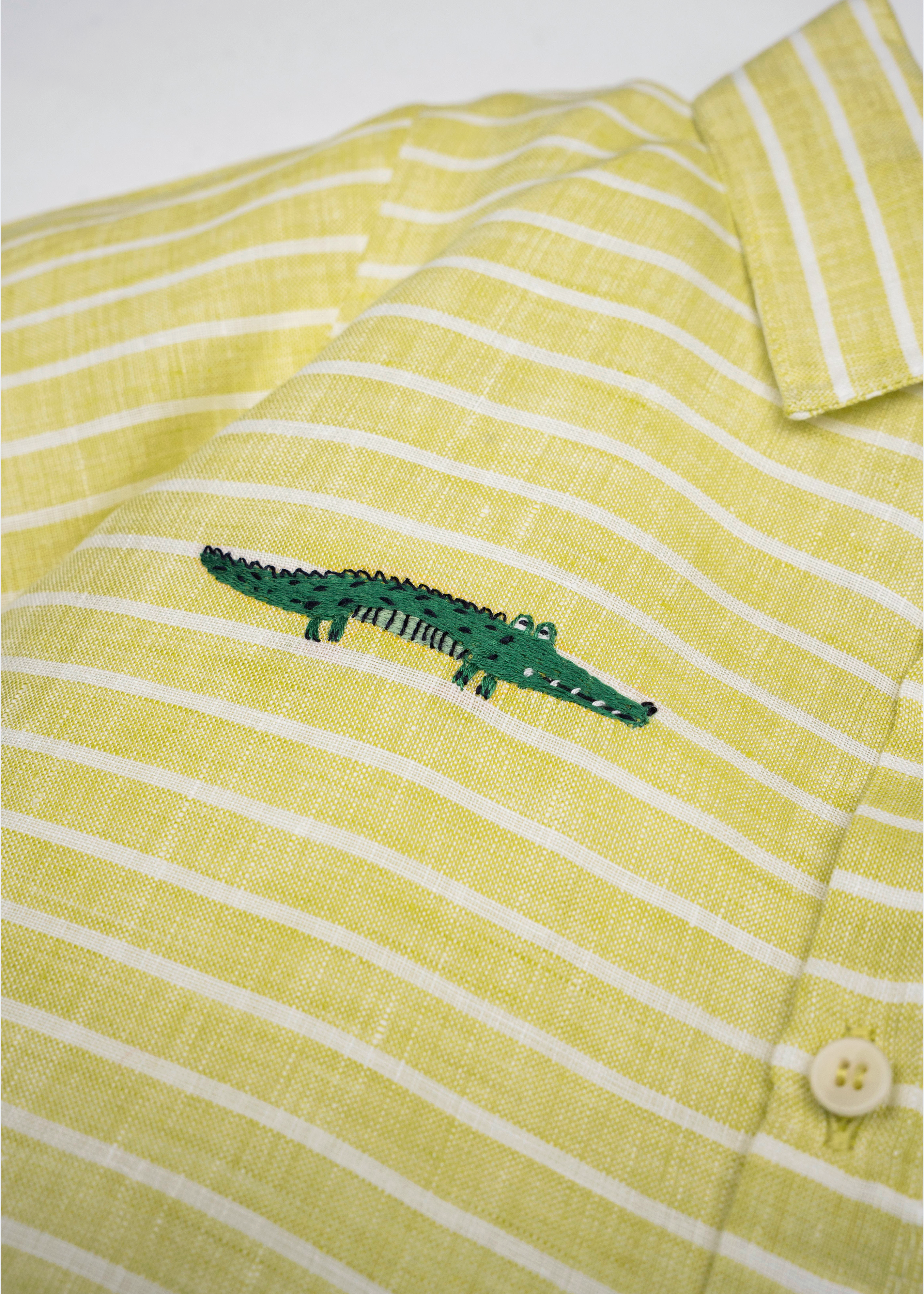 Detalhe da Camisa Tom infantil em linho listrado verde e branco com jacaré bordado à mão.