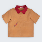 Camisa Luca infantil em 100% linho caramelo com gola vermelha, bolso frontal e cobra-coral bordada à mão, vista frontal.
