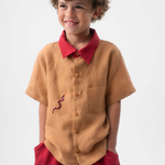 Detalhe da Camisa Luca infantil em linho caramelo vestida, com gola vermelha, bolso frontal e bordado de cobra-coral.