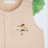 Detalhe de camisa infantil em linho puro com bordado à mão de jogadora de futebol e mangas de babados verde 