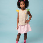 Menina usando camisa infantil em linho puro com mangas coloridas e bordado de jogadora de futebol, com saia listrada rosa