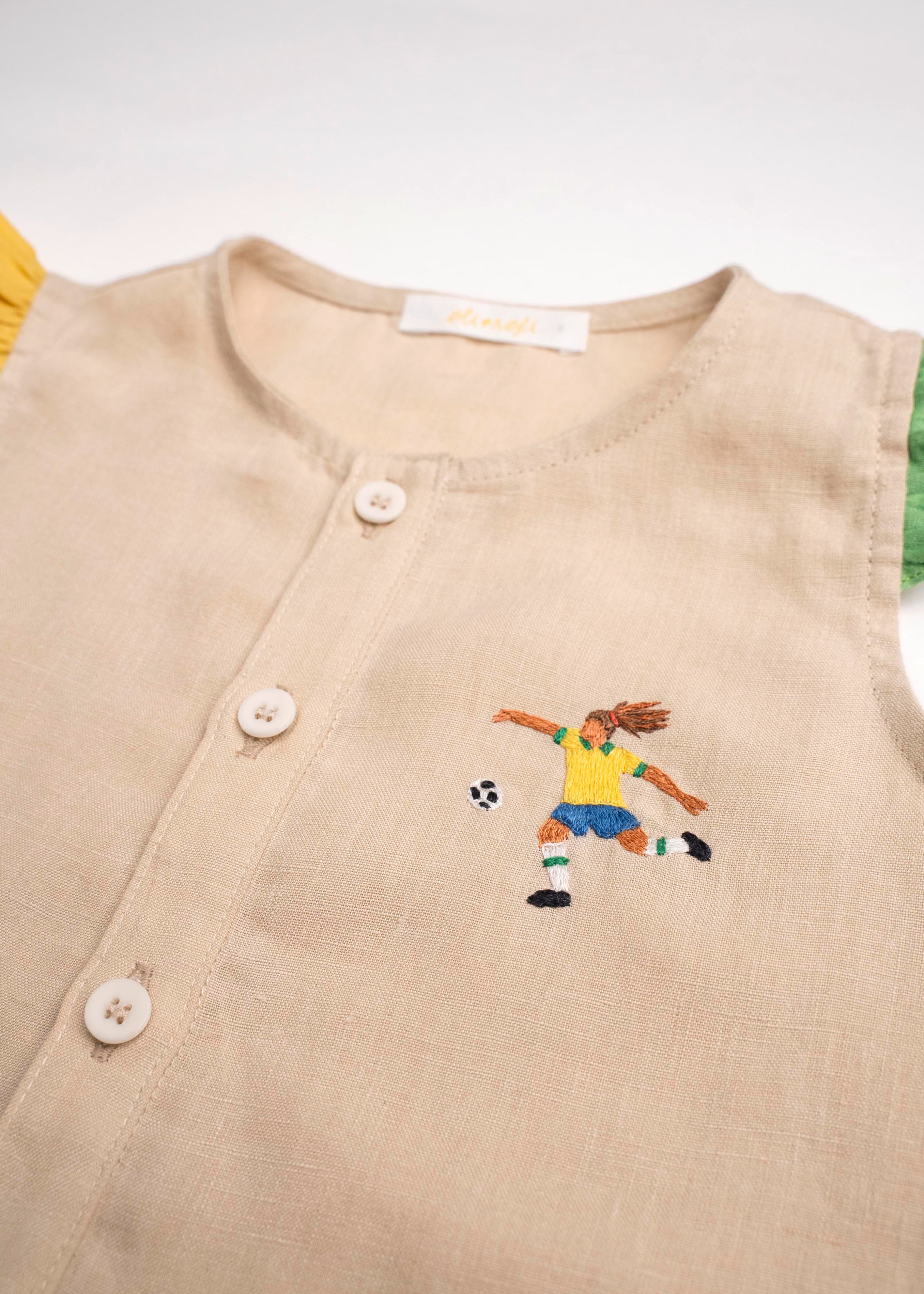 Detalhe do bordado à mão de jogadora de futebol em camisa infantil de linho puro